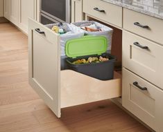 an open drawer in a kitchen filled with plastic containers and food items on top of wooden drawers