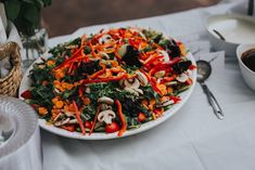 a plate full of salad with mushrooms and carrots on it next to a bowl of dipping sauce