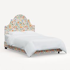 an upholstered bed with floral headboard and foot board in white linens