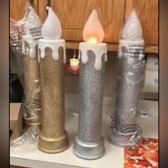 three candles are lined up on a counter top with plastic wrap around them and one candle is lit in the middle