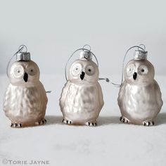 three silver ornaments with an owl on each ornament