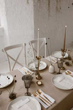 the table is set with white plates and candles