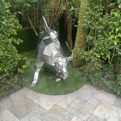 a metal cow statue sitting on top of a lush green field