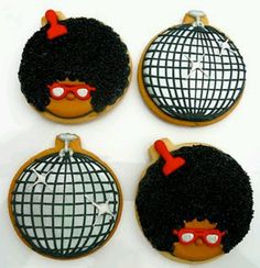 four decorated cookies with black hair and red glasses on top of each cookie, one has a disco ball in the middle