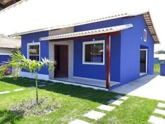 a small blue house sitting on top of a lush green field