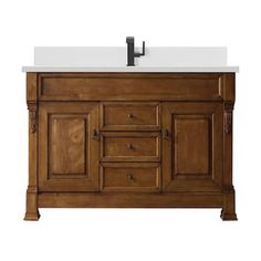 a bathroom vanity with a white counter top and wooden cabinetry on the bottom, along with a black faucet