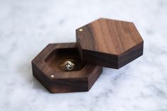 two wooden boxes sitting on top of a white counter with a diamond ring in the middle