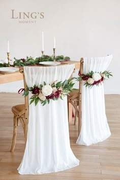 the table is set with white and red flowers on it, along with two chairs