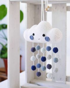 a crocheted cloud mobile with blue and white balls hanging from it's side