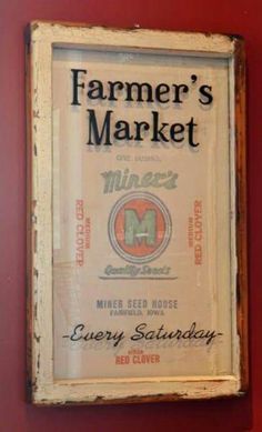 an old sign hanging on the side of a red wall that says farmer's market