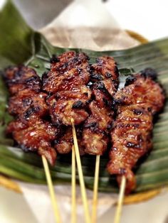 several skewers of meat on a banana leaf