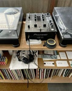 two turntables sitting on top of a wooden shelf filled with records and cds