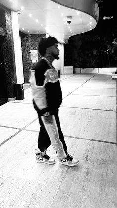 a man is walking down the street in black and white