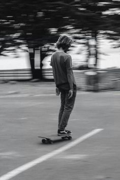 a young man riding a skateboard on top of a parking lot next to trees