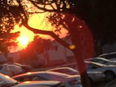 the sun is setting over a parking lot full of cars