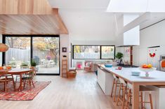 an open concept kitchen and dining room with hardwood floors, white walls, and wooden ceilinging