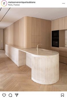 an empty kitchen with wooden flooring and white marble counter tops, along with wood paneling on the walls