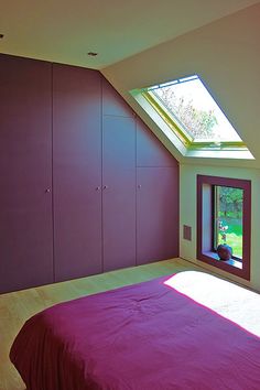 a bedroom with purple walls and a skylight