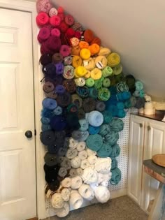 there are many balls of yarn on the wall next to the door and table in front of it