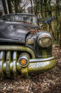 an old car that is sitting in the woods