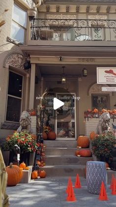 the front entrance of a store with pumpkins and flowers on display in orange cones