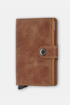 the brown leather wallet is open and has a metal clip on it's side