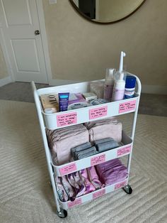 a white cart filled with lots of items on top of a carpeted floor next to a mirror