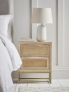 a bedroom with a bed, nightstand and lamp on the side table in front of it