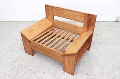 a wooden bed frame sitting on top of a cement floor next to a white wall