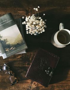 a book, sunglasses, and cup of coffee on a wooden table