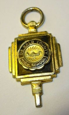 a gold keychain with the words denka's central high school on it