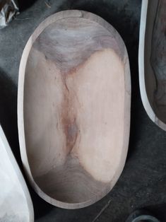 a wooden bowl sitting on top of a floor next to other wood bowls and spoons