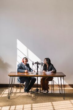 two people sitting at a table with microphones