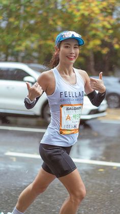 a woman running in the rain with an umbrella on her head and one hand up