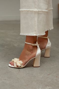 a woman's feet wearing high heels with flowers on the heel and ankle straps