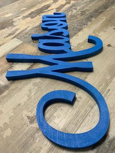 a wooden sign that is sitting on top of a wood floor and has the word's name spelled in blue