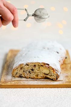 a person is sprinkling icing onto a loaf of bread on a cutting board