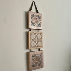 three wooden plaques hanging on the wall with beaded string attached to them, each displaying an intricate design