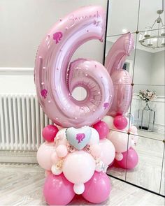 the number six balloon is in front of a mirror with pink and white balloons on it