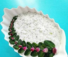 a bowl filled with cream and flowers on top of a blue table