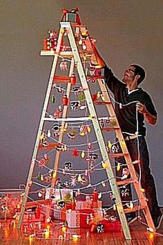 a man standing next to a ladder decorated with christmas lights