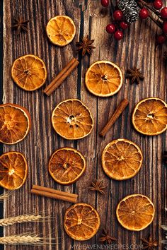 an assortment of orange slices and cinnamons arranged on a wooden table with spices, star anisettes and berries