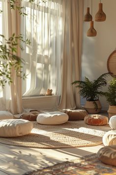 a living room filled with lots of pillows and plants in front of a large window