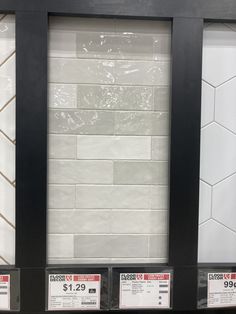 three black frames with white subway tiles on them for sale in a store or restaurant