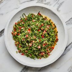 a white bowl filled with salad on top of a marble counter