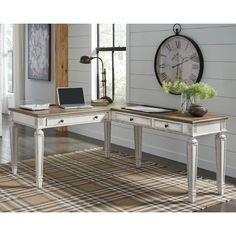 a desk with a laptop on it in front of a clock