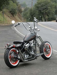 a black and red motorcycle parked on the side of the road next to a hill