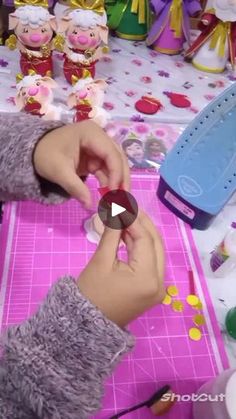 a person is making some decorations on a pink table with stuffed animals and other toys