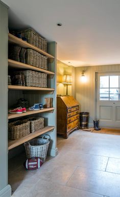 an empty room with lots of shelves and baskets on the floor in front of a door