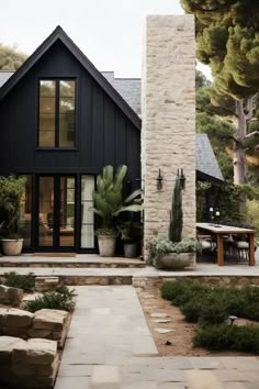 a house that has some plants in the front and side of it with rocks on the ground